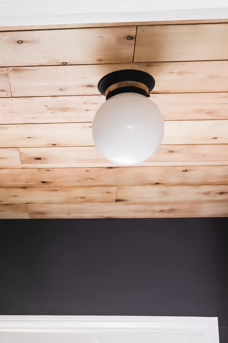 spray painted light fixture hanging from wood ceiling