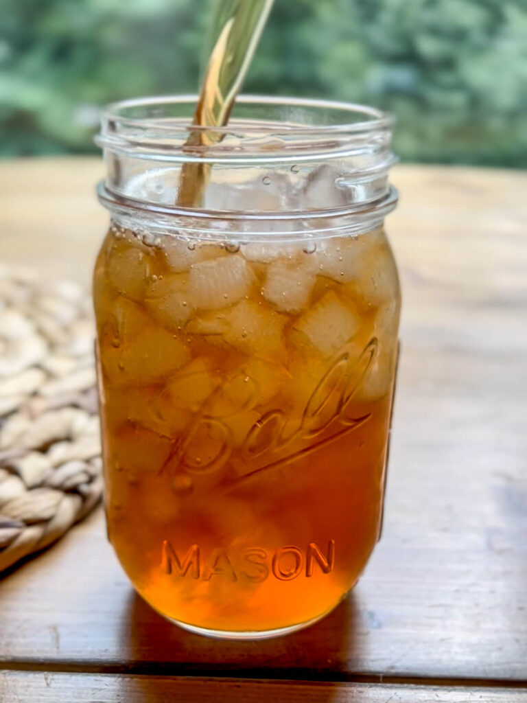 glass of sweet tea being poured into a ball jar used as a drinking glass