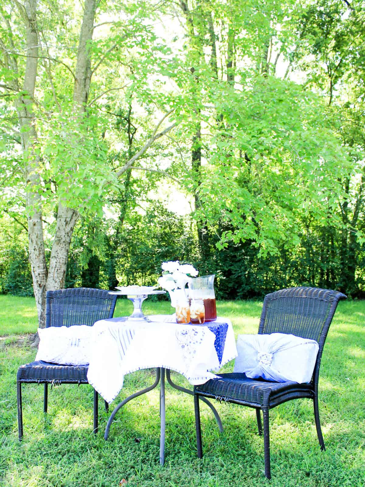 outdoor table with blue tablecloth with a pitcher of sweet tea with 2 full glasses