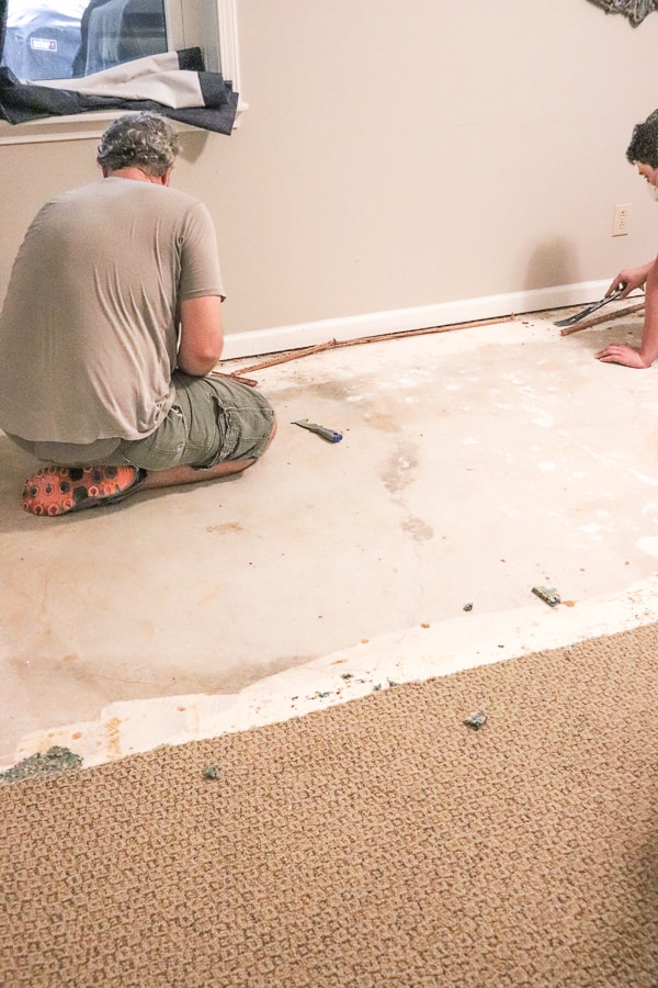 men removing tack strips from a concrete subfloor