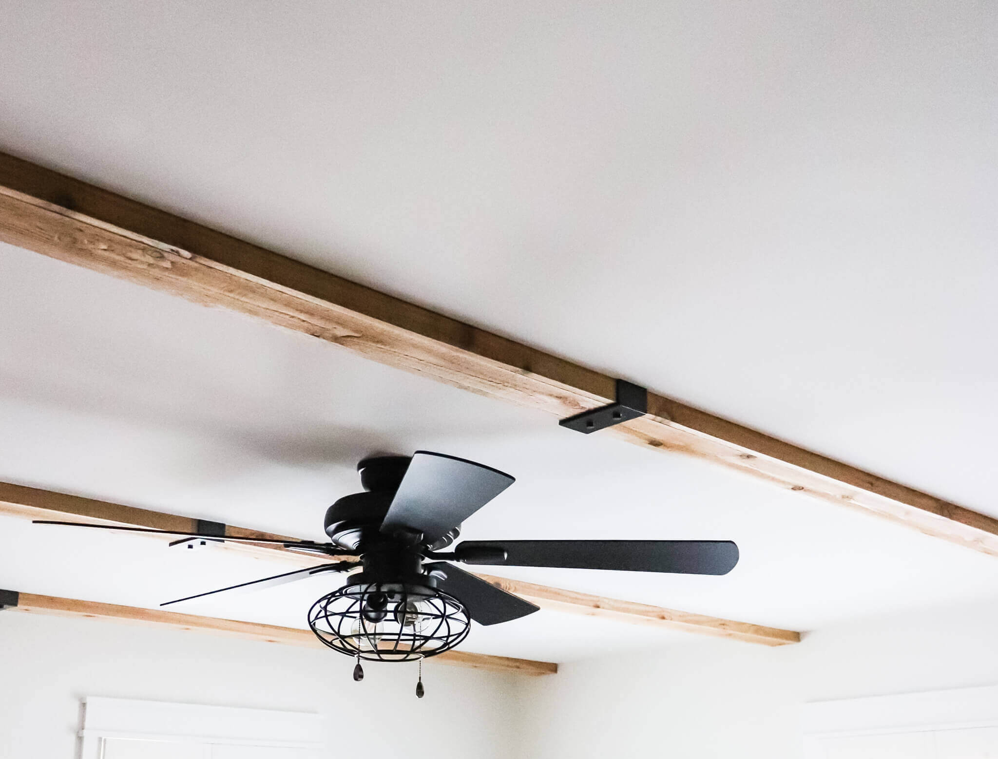 wooden ceiling beams with a black ceiling fan