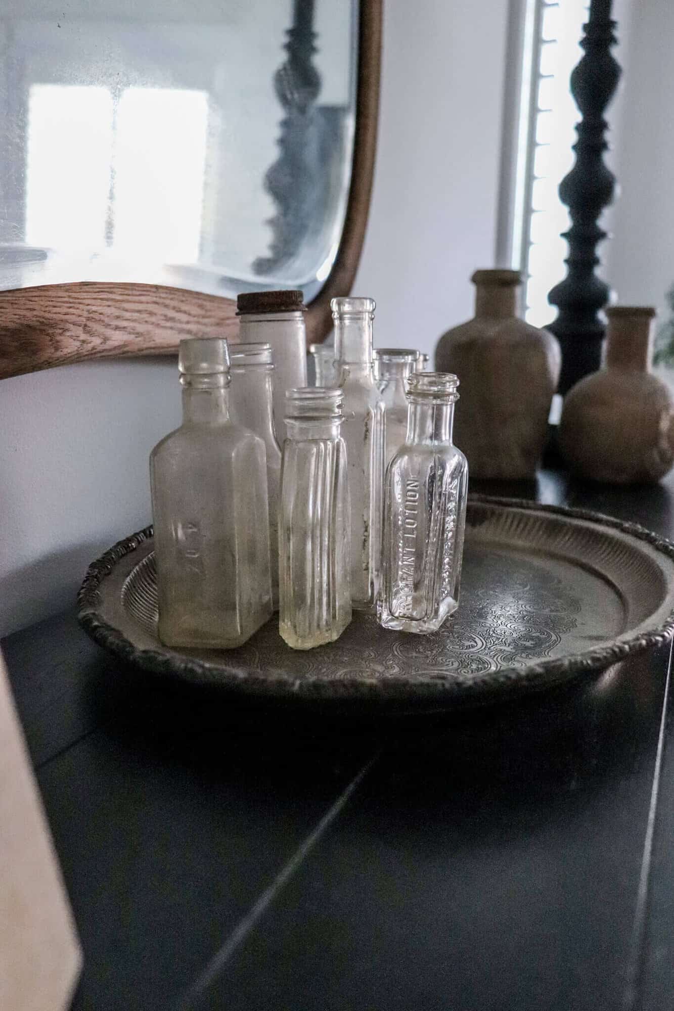 Old silver tray with vintage medicine bottles sitting on a black dresser