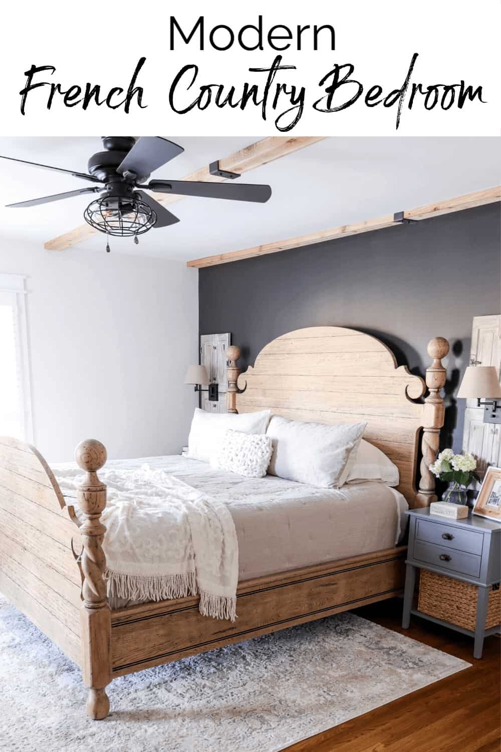 bedroom decorated with a modern French country style with cedar ceiling beams, black accent wall, and cannonball unfinished bed with tan bedding