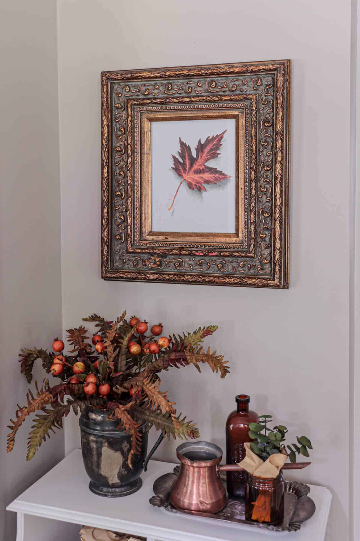 brass frame with leaf picture hanging in an entryway