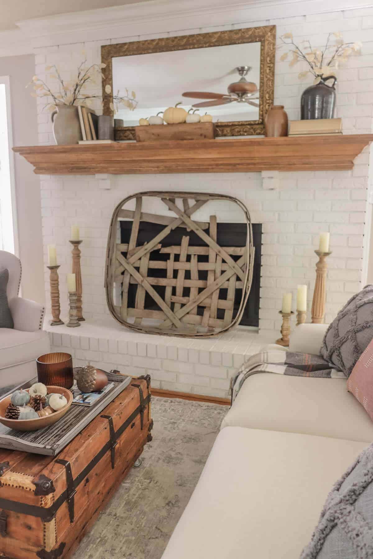 white fireplace painted with Romabio masonry flat with a tobacco basket as a screen and a fall decorated mantel with old books and crocks and gray fall decor