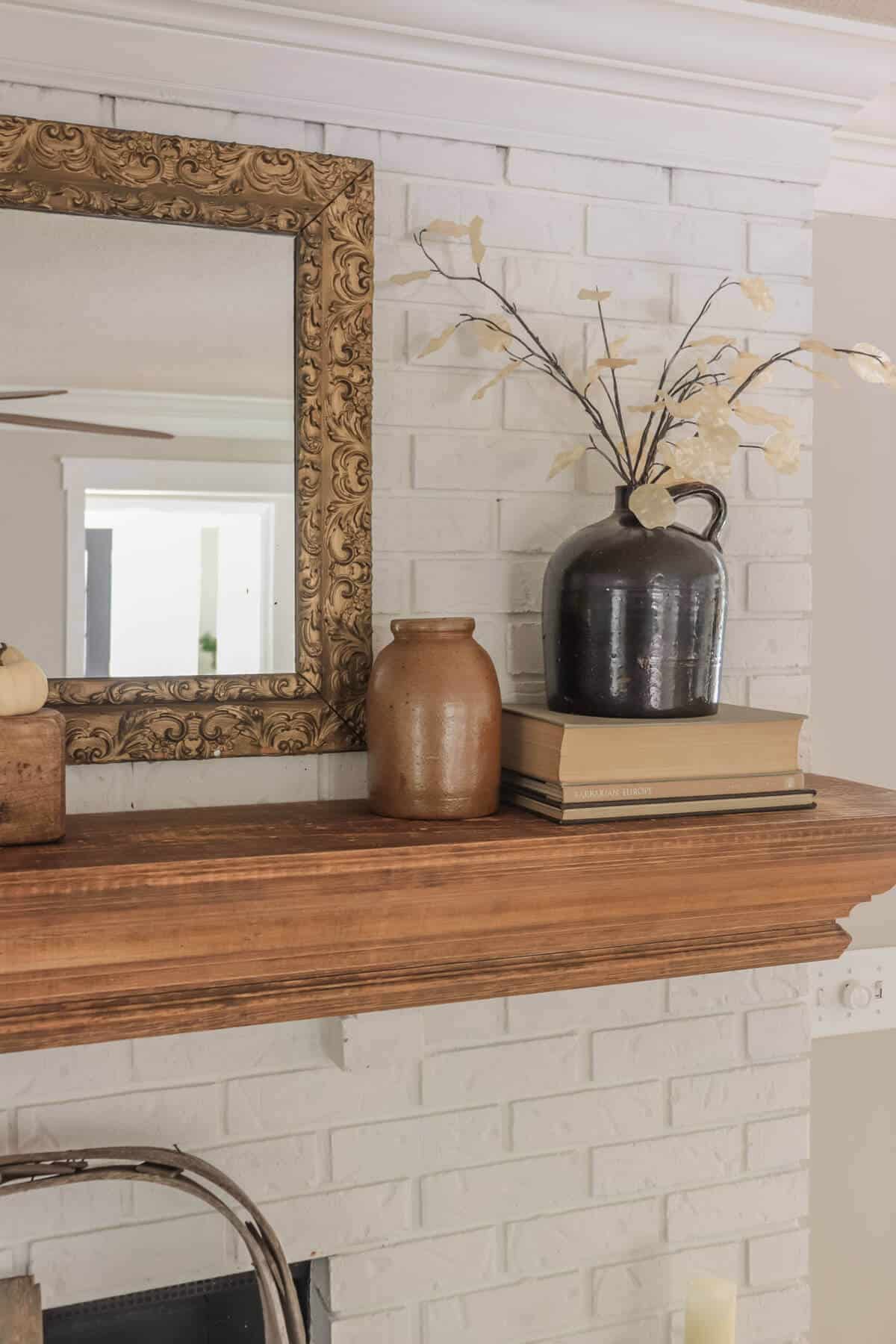 white fireplace painted with Romabio masonry flat with a tobacco basket as a screen and a fall decorated mantel with old books and crocks