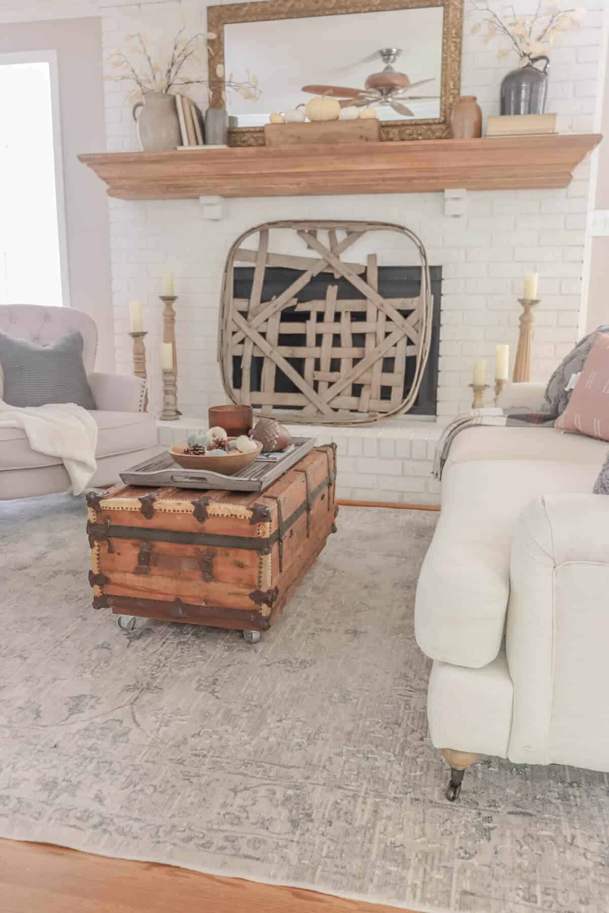 white fireplace painted with Romabio masonry flat with a tobacco basket as a screen and a fall decorated mantel with old books and crocks