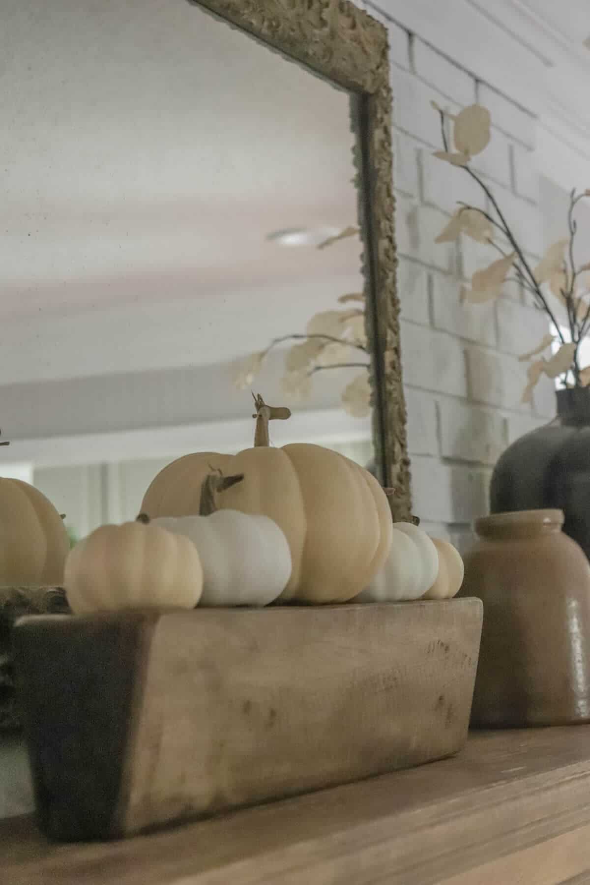 Cream and white pumpkins sitting on top of vintage sugar mold on a mantel