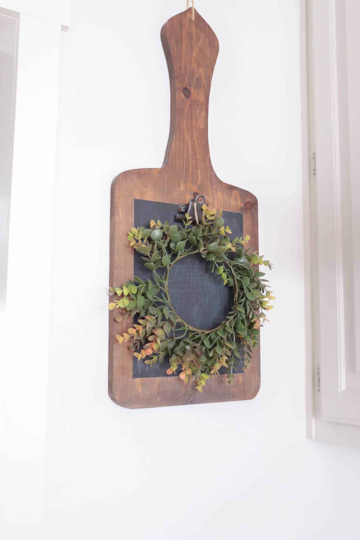cutting board hanging on a wall with a fall wreath