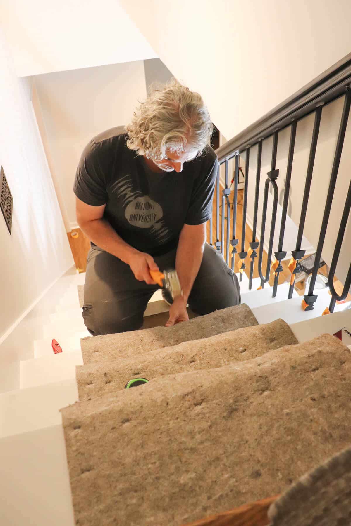 attaching carpet pad to stair treads using a hammer tacker