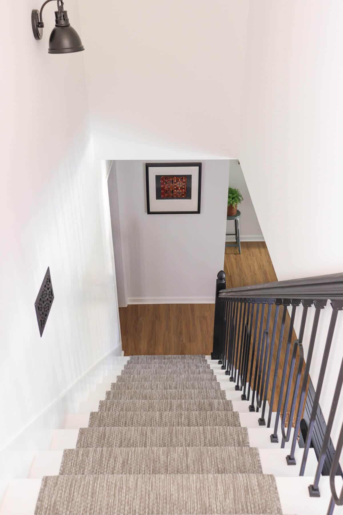 updated basement stairway with gray carpet runner, fresh paint and new black iron balusters