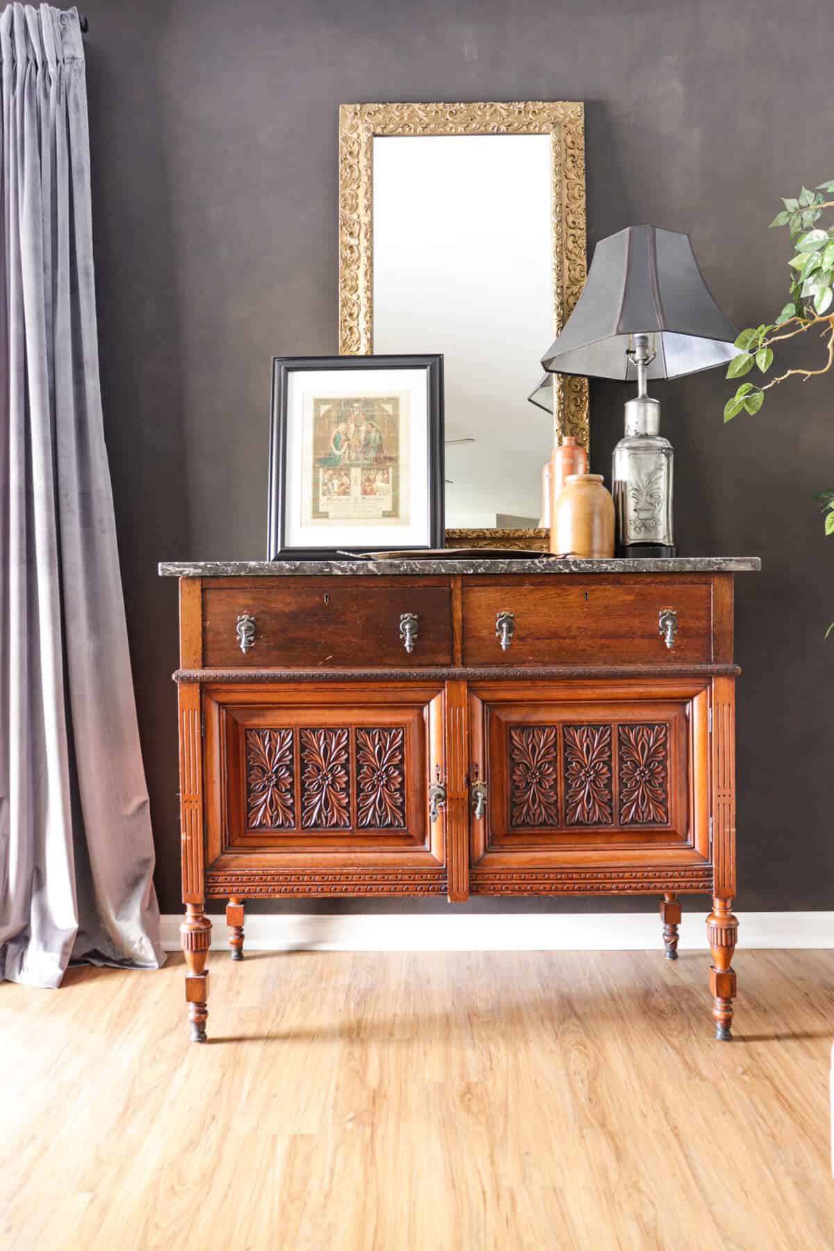 vintage wooden chest with ornate carvings in front of dark accent wall
