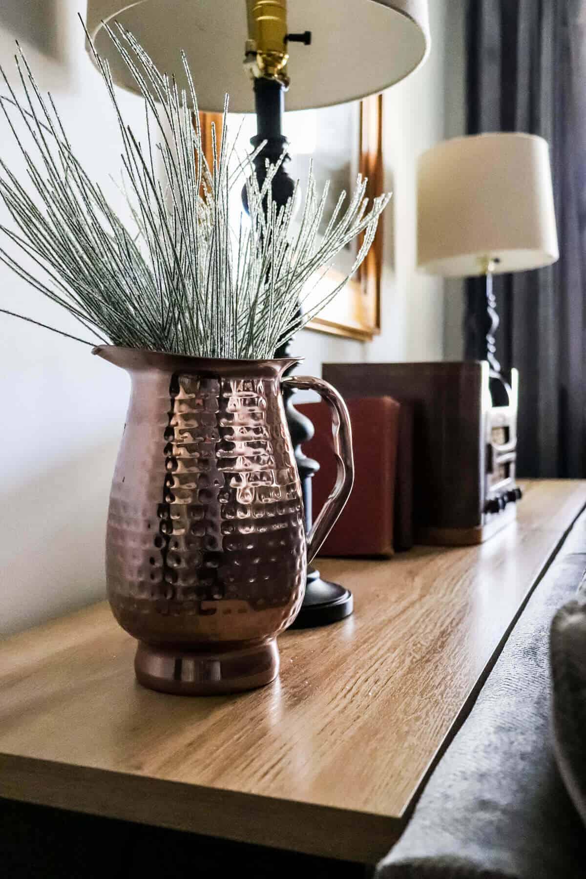 copper pitcher filled with iced greenery for Christmas