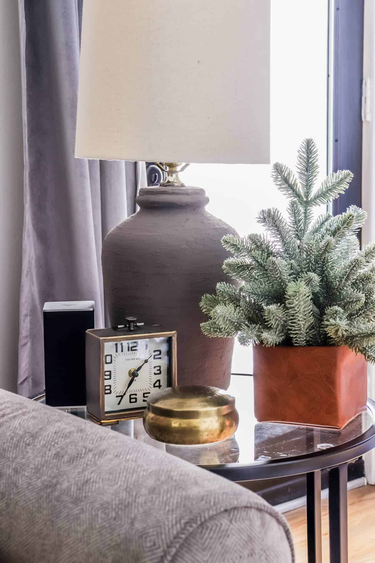 side table with painted lamp and small tree in leather box