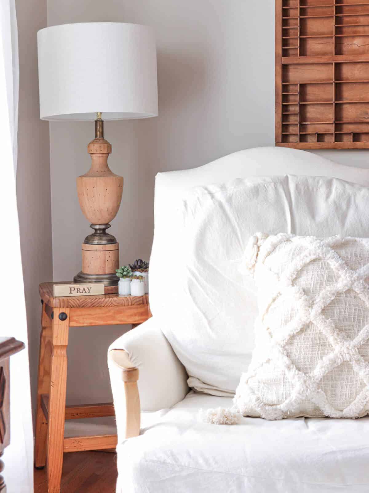 wooden lamp on a stool next to a white armchair