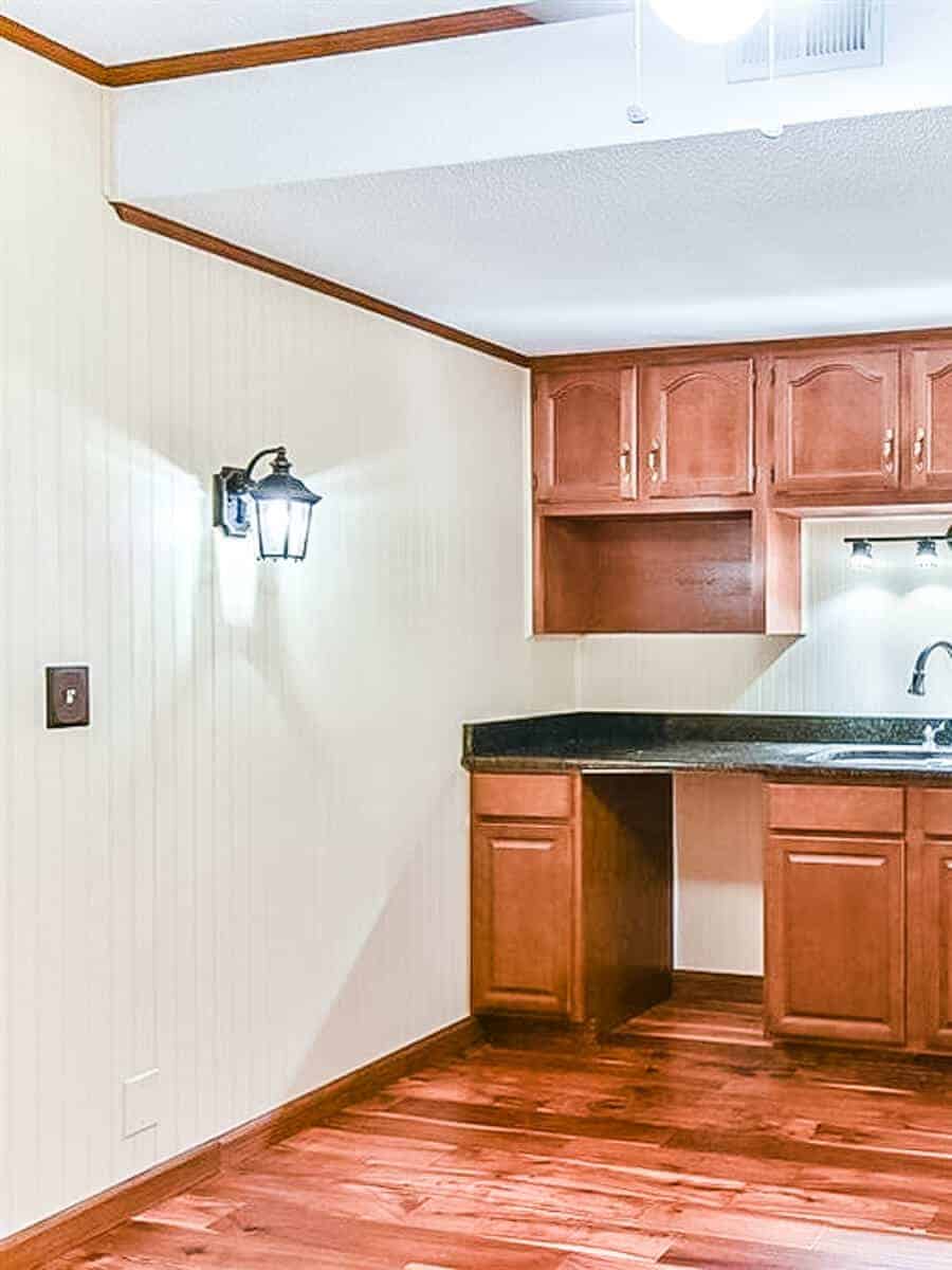 Dated 80s basement kitchenette with bead board walls and popcorn ceiling