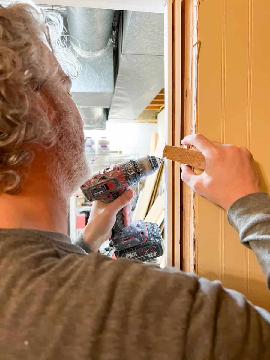 a man drilling shims to frame up an interior door