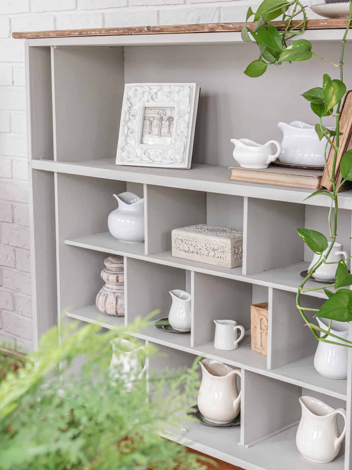 a bookcase filled with vintage creamer pitchers