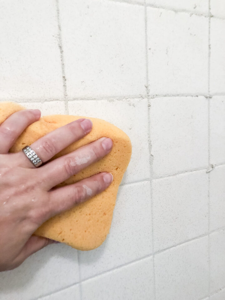 wiping away excess grout with a yellow sponge