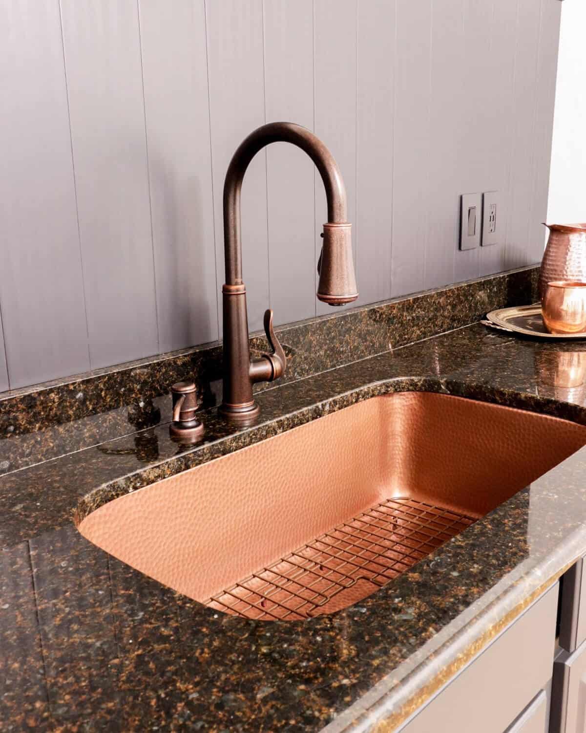 gray cabinetry with a copper sink and faucet