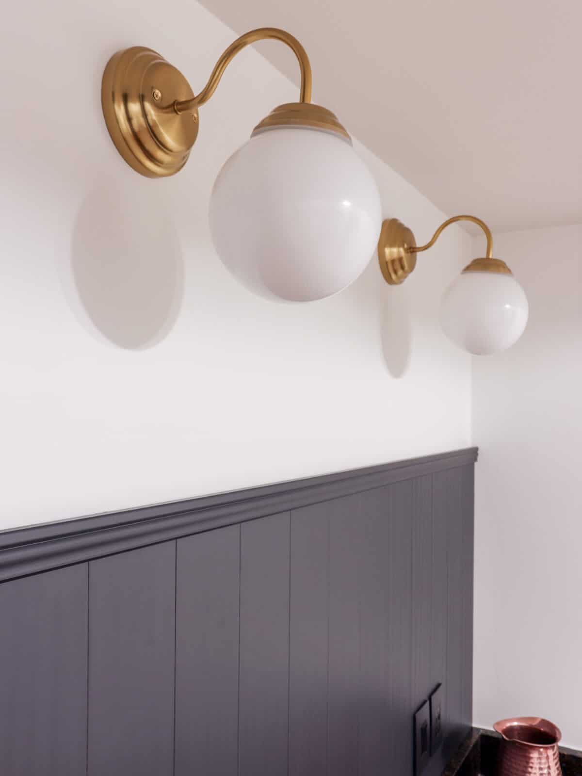Gray backsplash with brass harp lights with white round globes