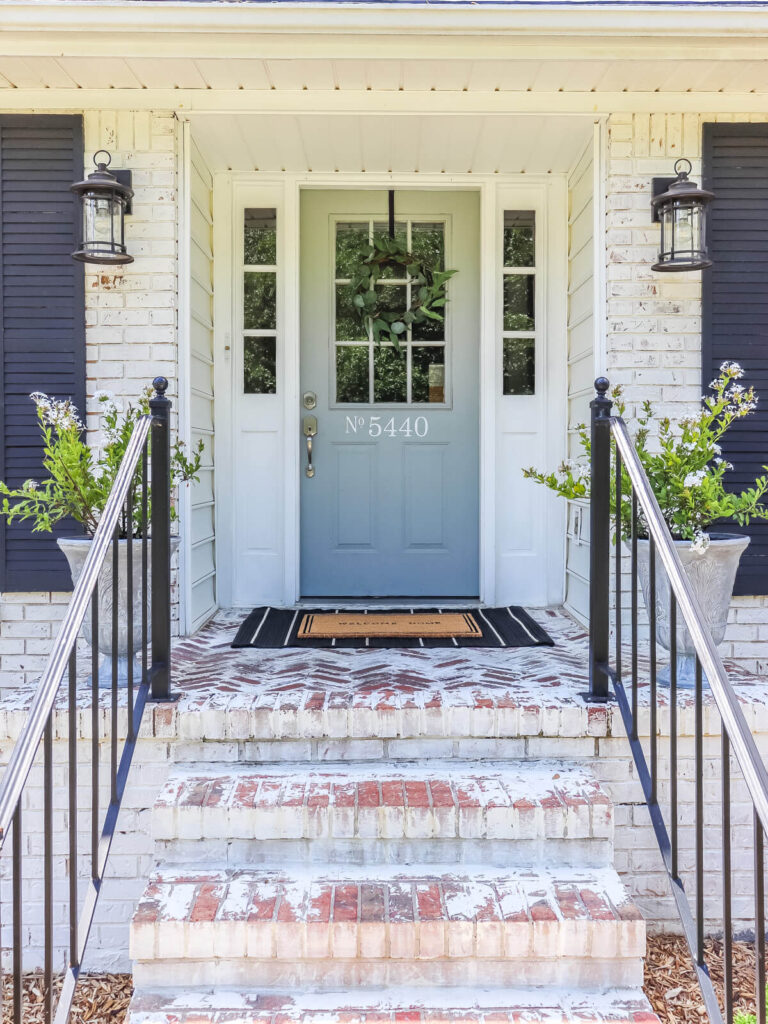 light gray front door with wreath and layered door mats