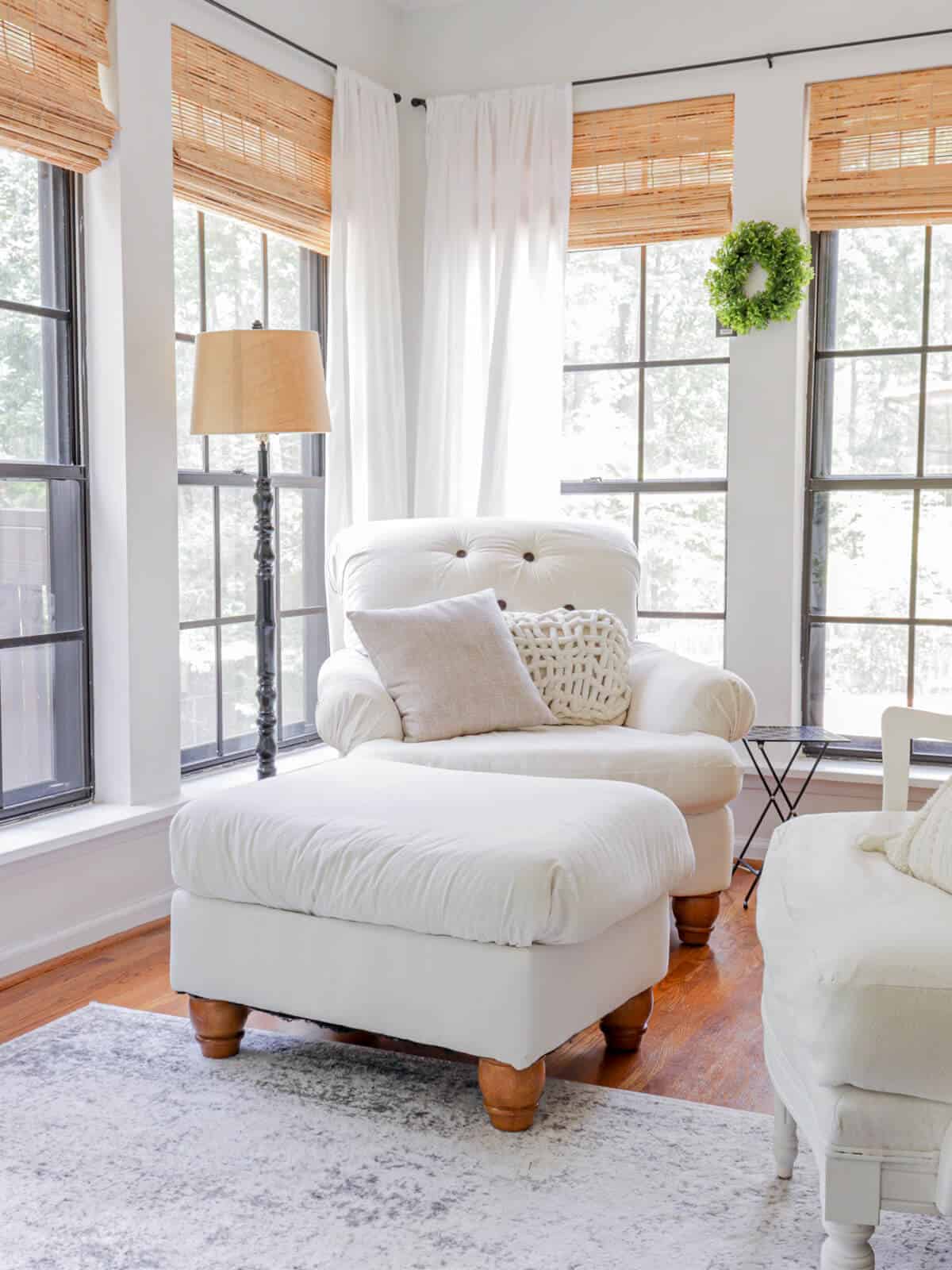 light and bright sunroom with woven wood shades and a tufted armchair