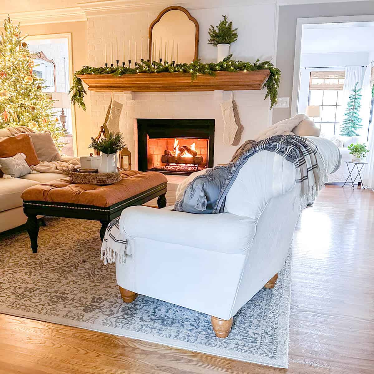 View of holiday fireplace with stocking and lit christmas tree