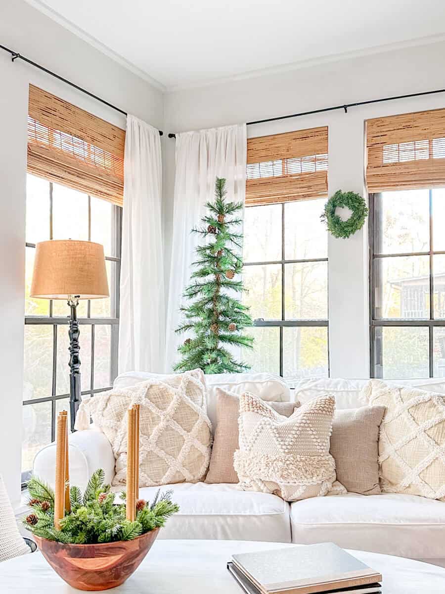 sunroom with black windows and white furniture decorated for winter