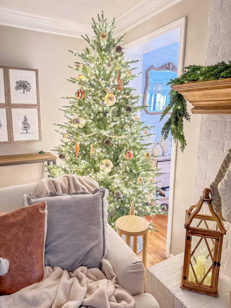 Christmas tree next to a fireplace and couch with blankets