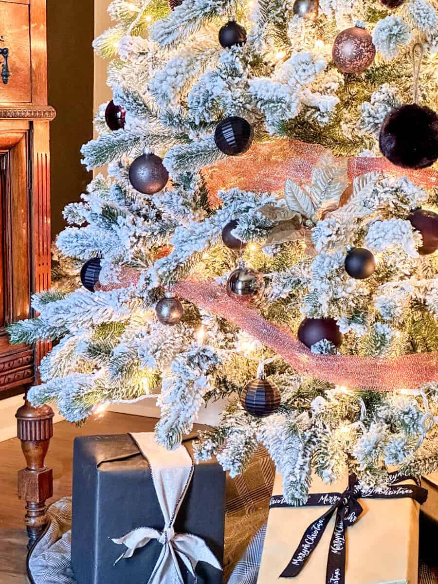 flocked white tree next to a black accent wall decorated with black and copper ornaments
