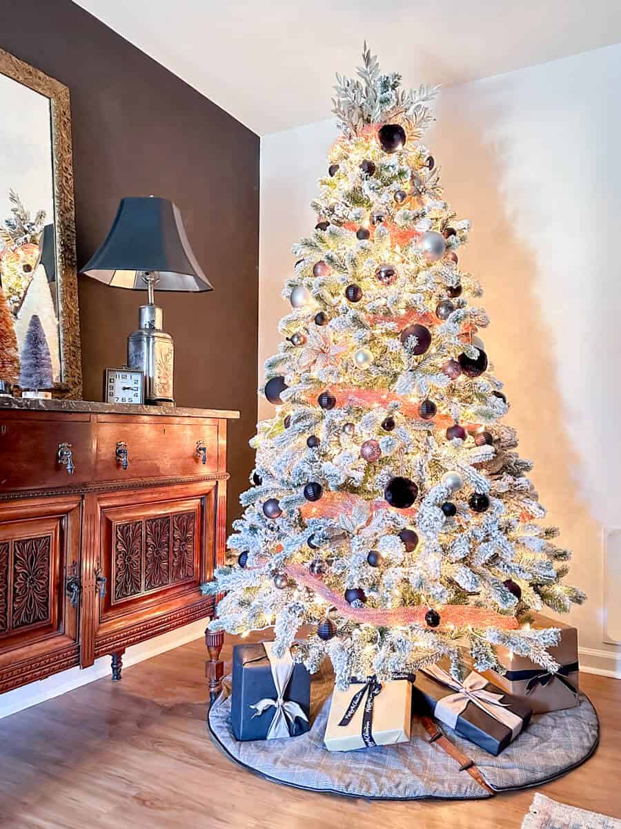 flocked white tree next to a black accent wall decorated with black and copper ornaments