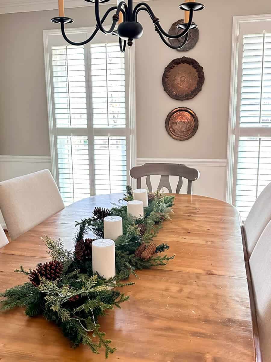 dining table with winter garland and white pillar candles as a centerpiece