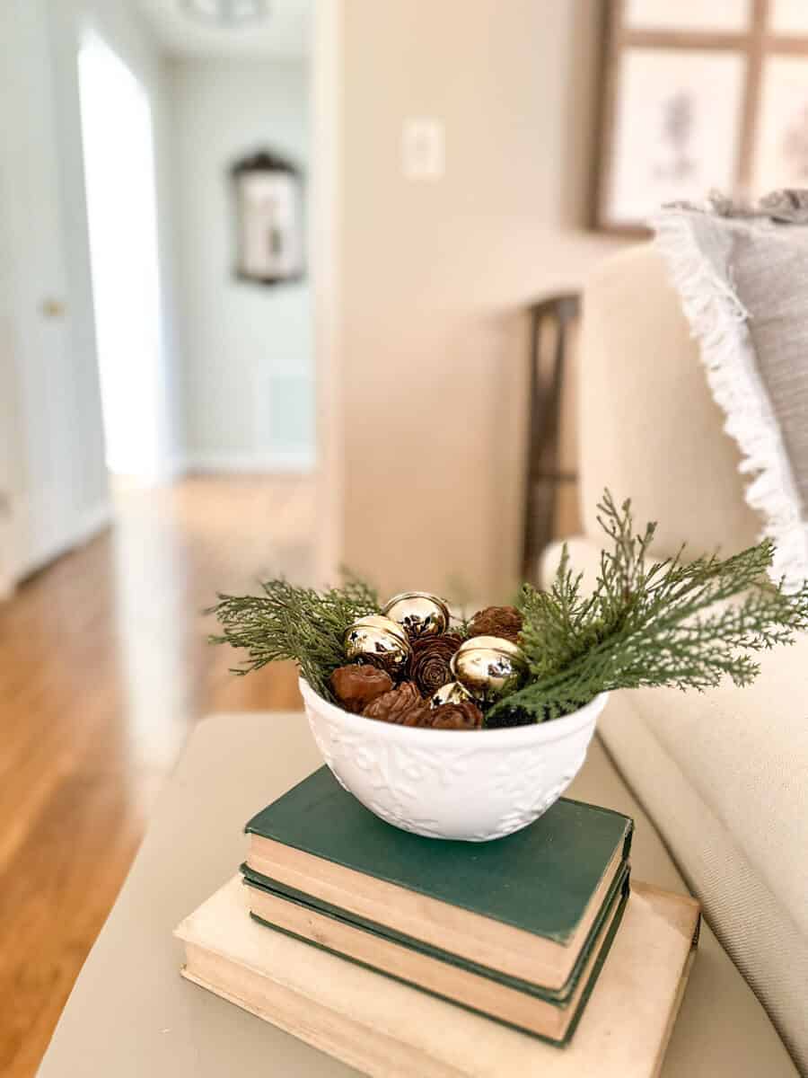 snowflake dish filled with greenery and bells sitting on books