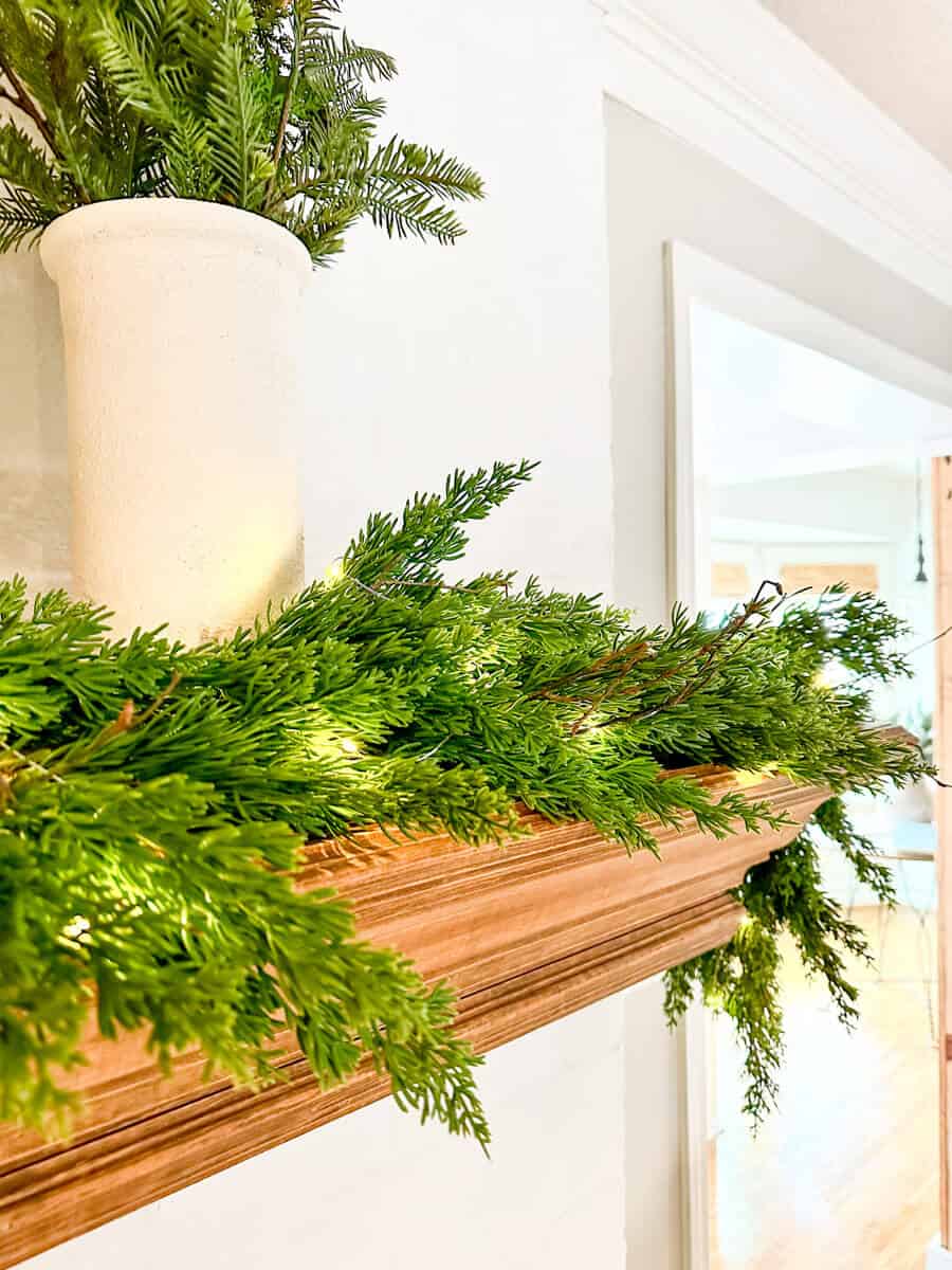 faux cedar garland with metal iron candelabra in front of a mirror on a mantel
