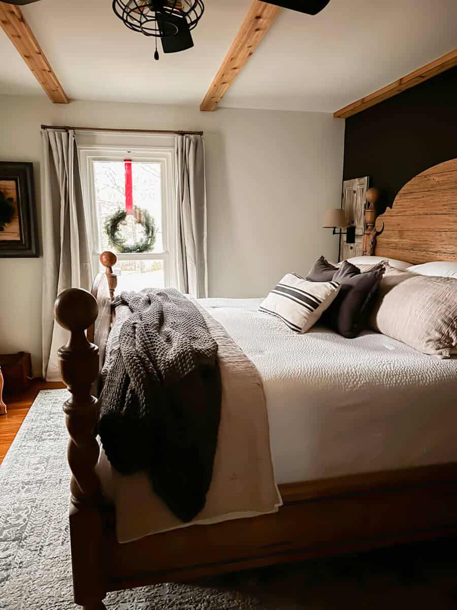 four poster cannonball bed against a black wall with white, beige and charcoal bedding