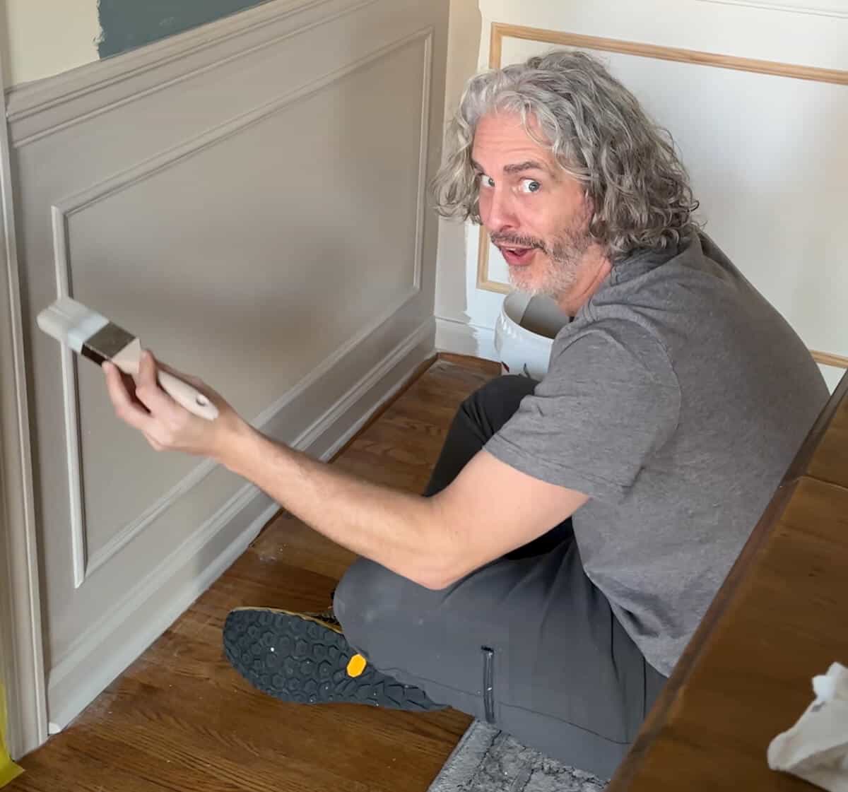 man making silly face while painting wainscoting