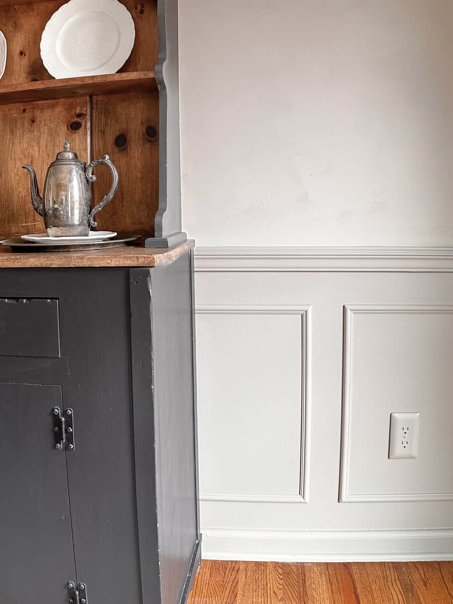 painted wainscoting in dining room next to a dark gray hutch