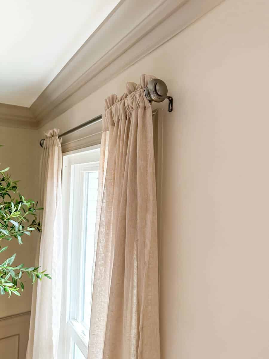 Linen curtains in a dining room hung on limewashed walls in a taupe color