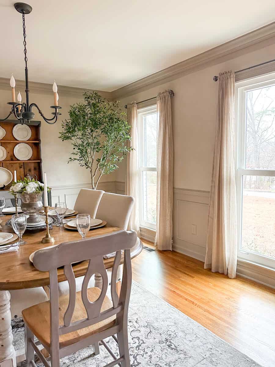Linen curtains in a dining room hung on limewashed walls in a taupe color