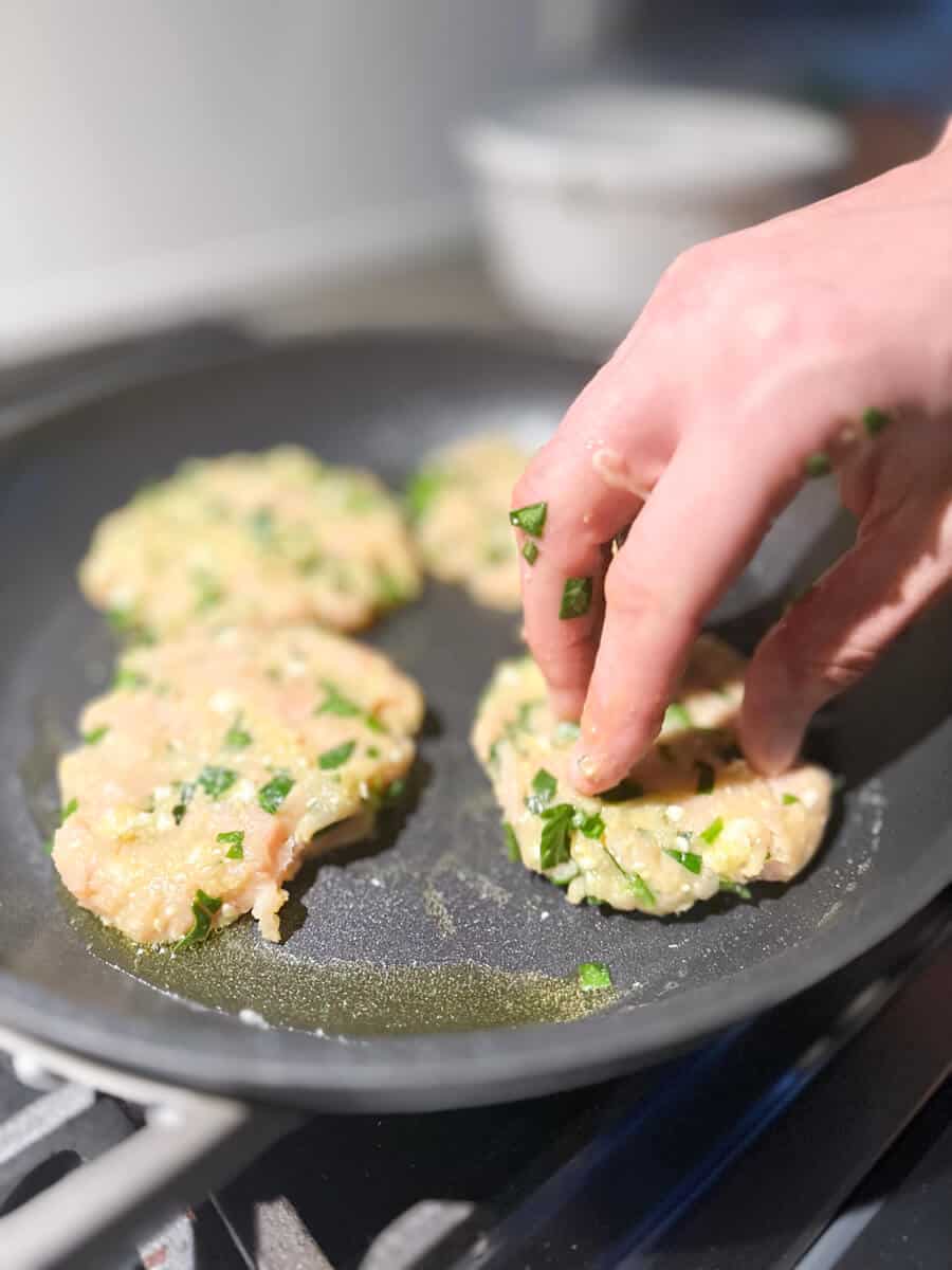 adding chicken burgers to frying pan