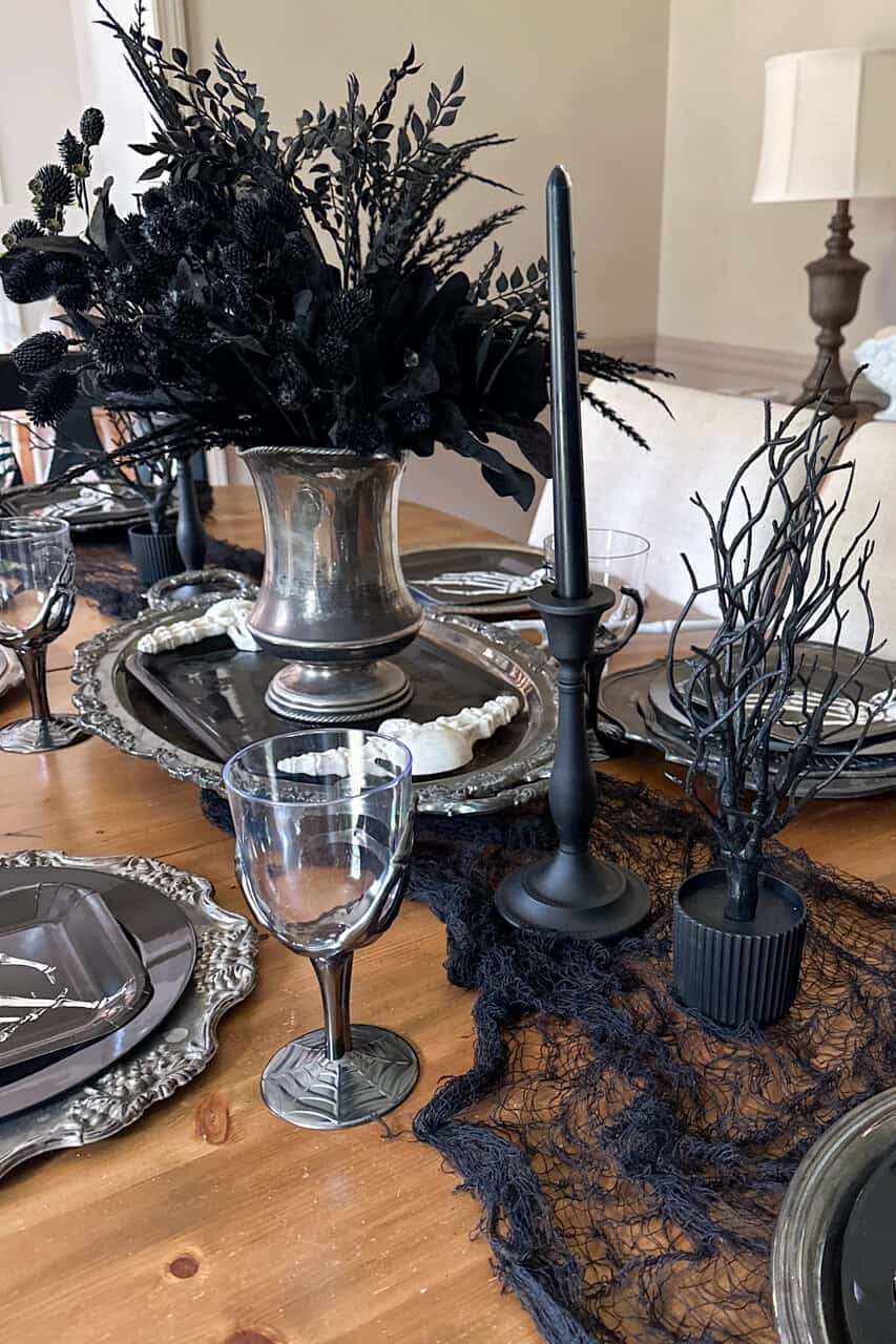 Halloween centerpiece with a tarnished silver pitcher filled with faux black greenery