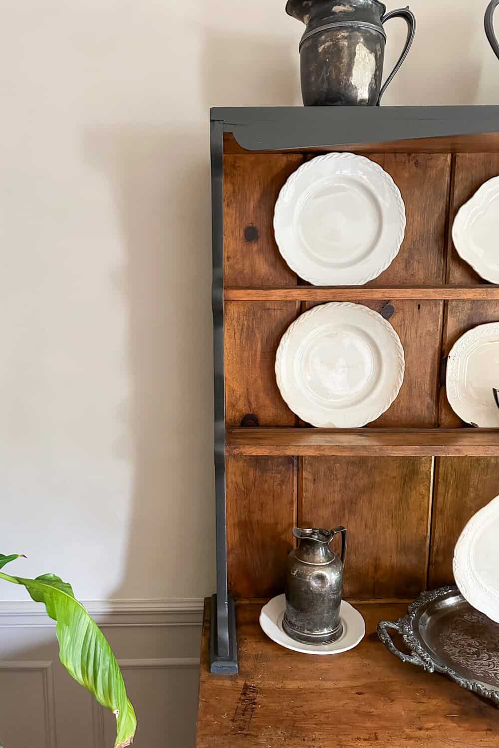 vintage hutch with ironstone plates and old silver in front of a limewashed wall