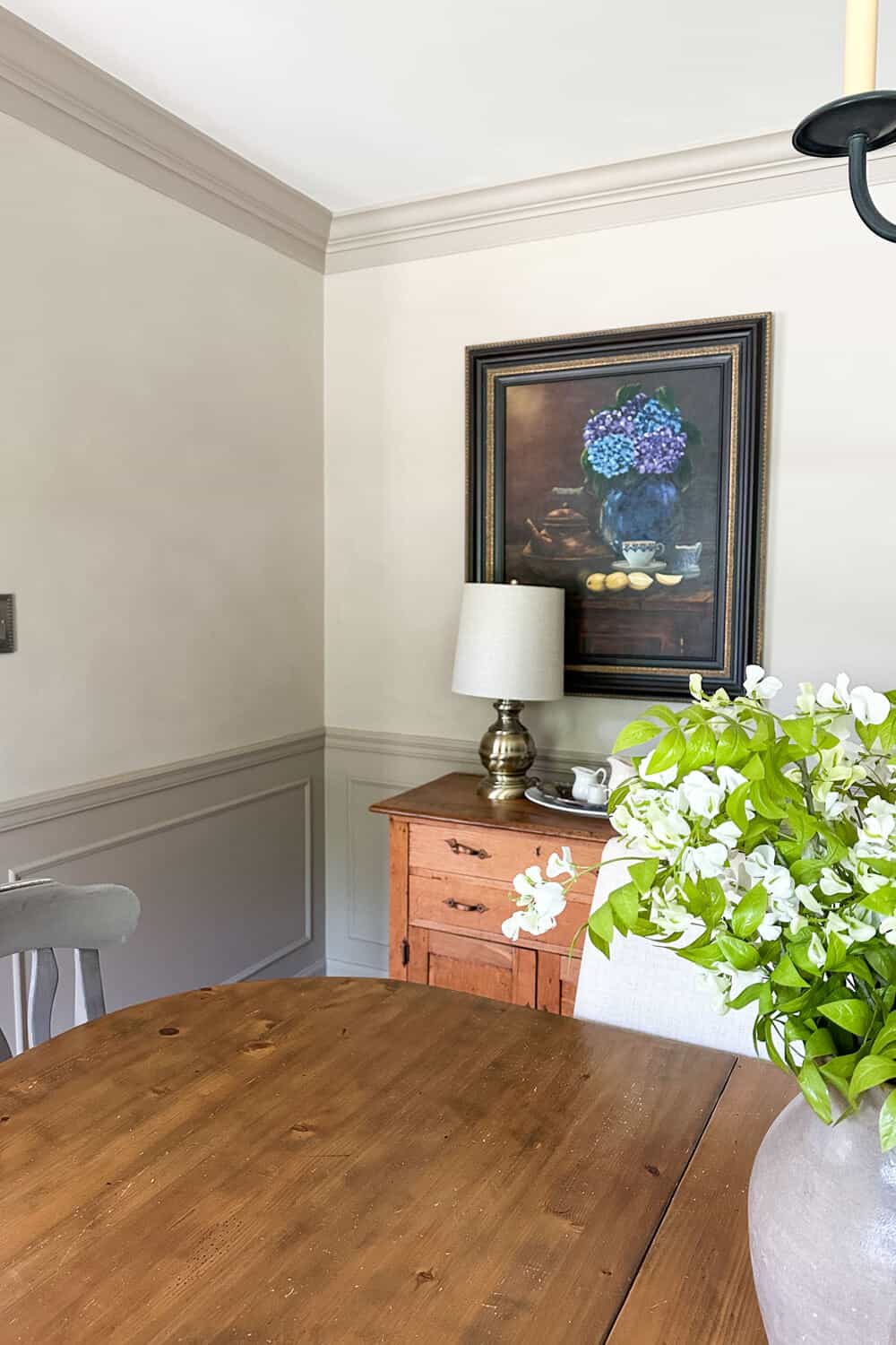oil painting with hydrangeas hanging on a limewashed wall in a dining room