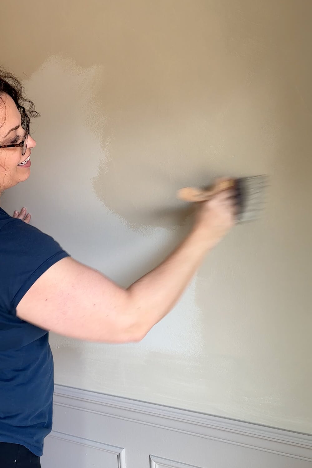 woman with glasses lime washing a wall