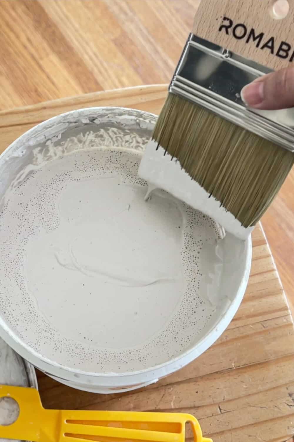 dipping a spalter brush into a bucket filled with limewash paint