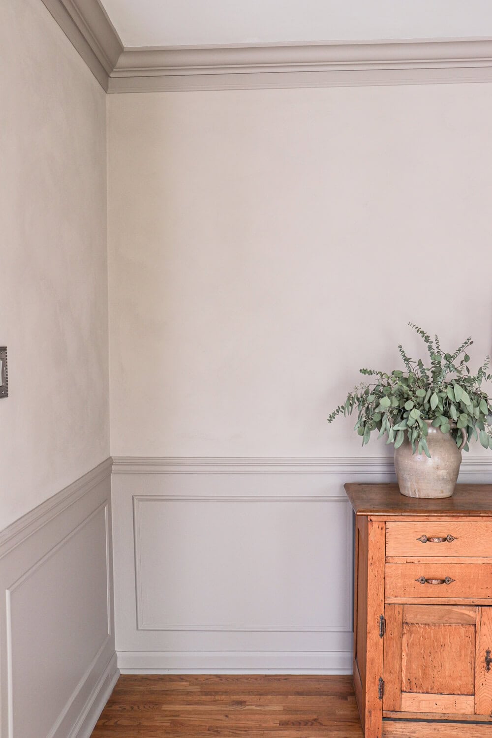 limewashed walls with cabinet in front with pottery jug holding dried eucalyptus