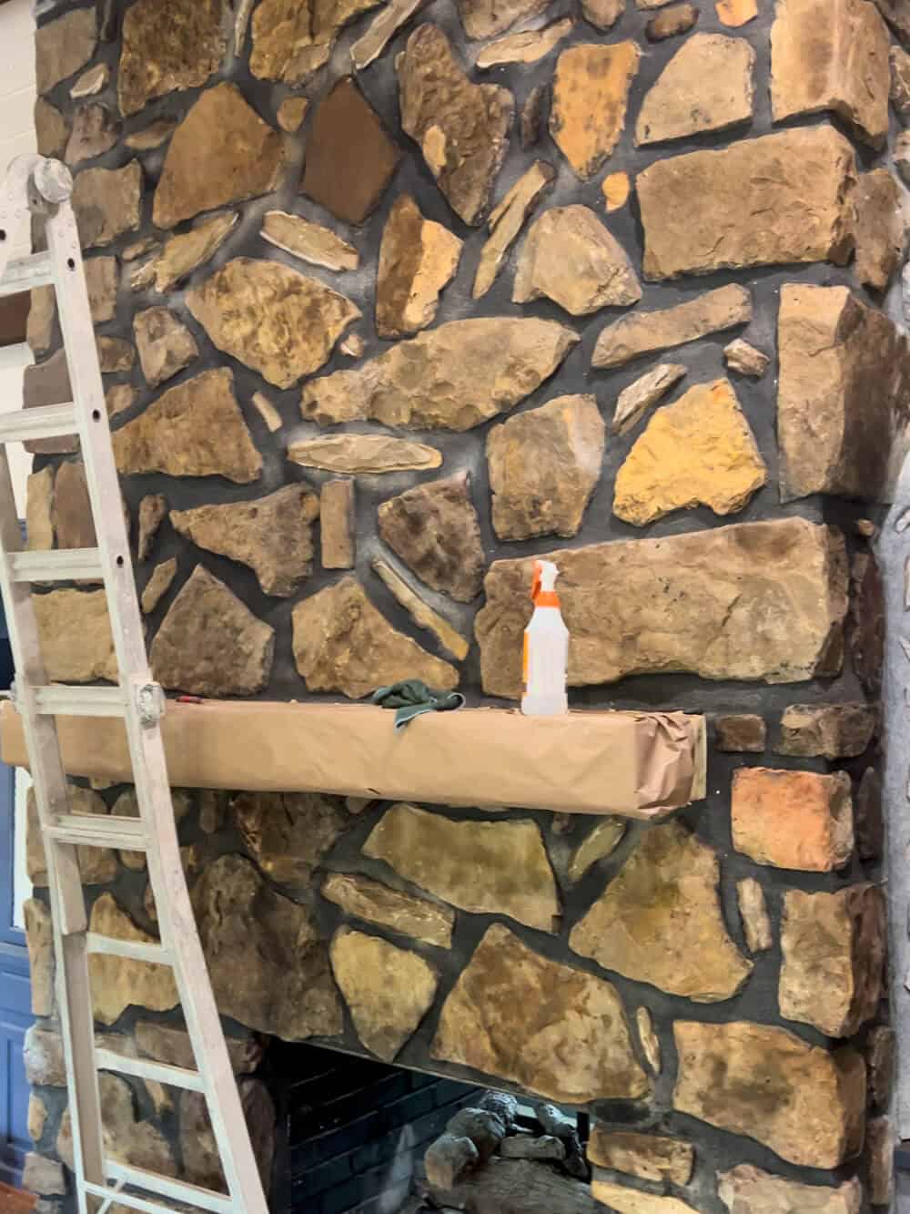 A ladder is being used to clean a stone fireplace.