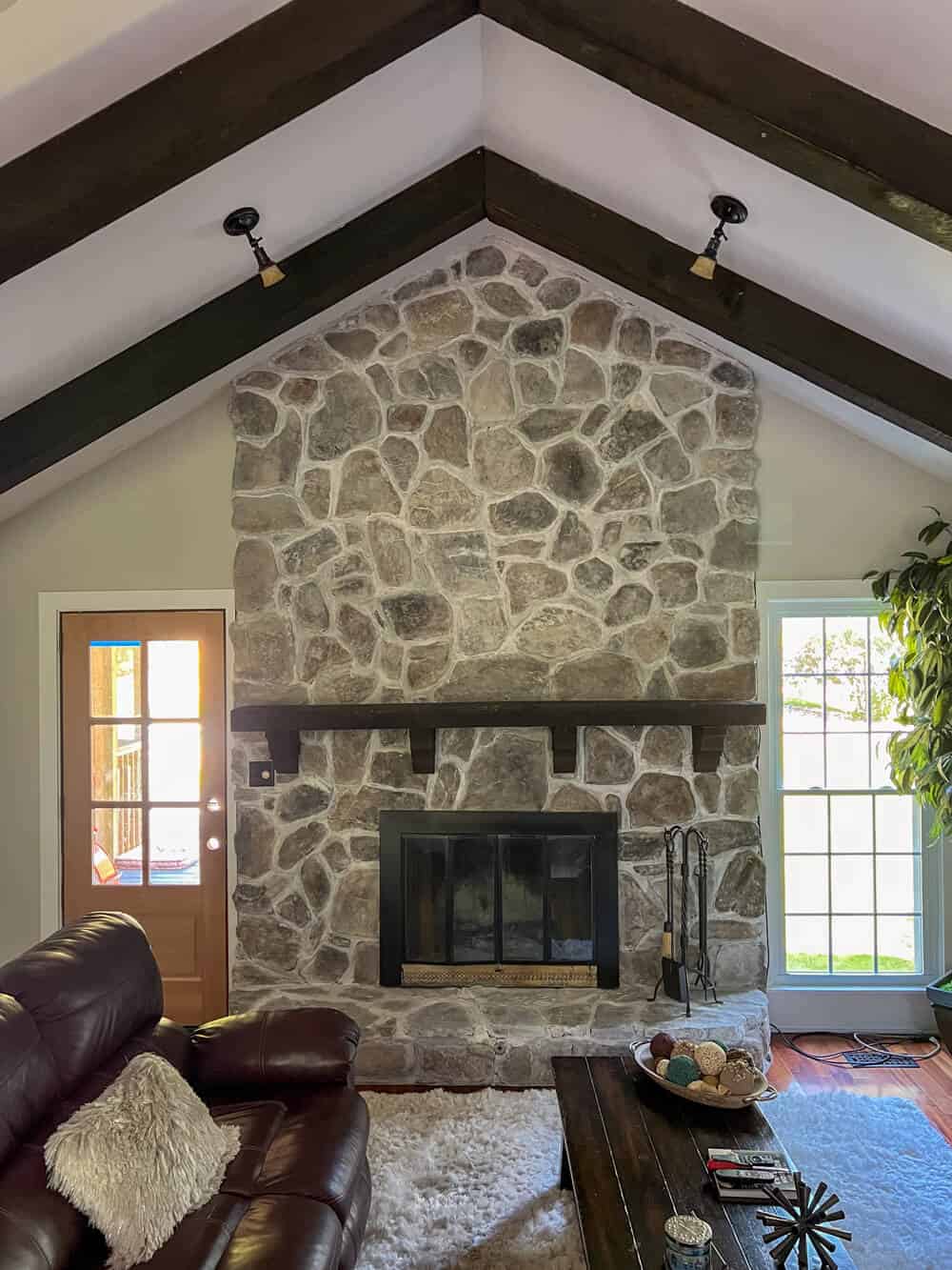A living room with a limewashed stone fireplace and leather couches.